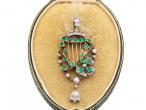 Emerald and diamond harp brooch in yellow gold and silver with articulated diamond drop.