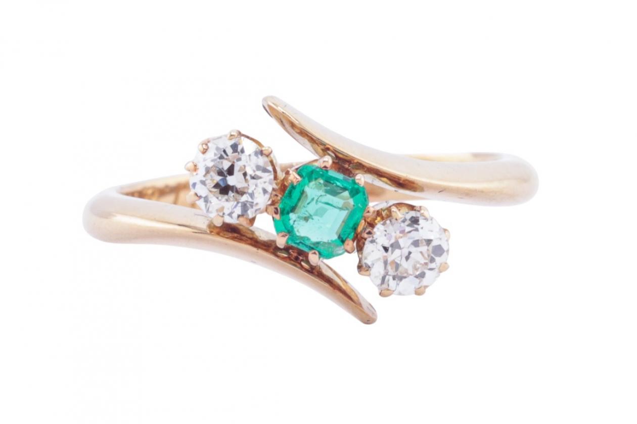 EDWARDIAN EMERALD AND DIAMOND THREE-STONE CROSSOVER RING, 1909