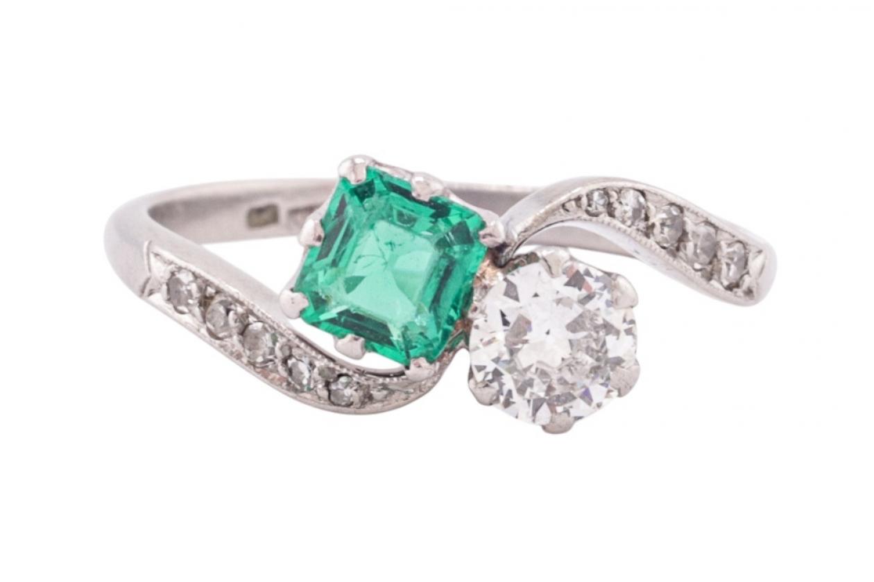 EDWARDIAN DIAMOND AND EMERALD CROSS-OVER RING, CIRCA 1910