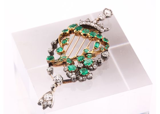 Emerald and diamond harp brooch in yellow gold and silver with articulated diamond drop.