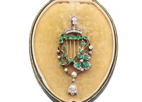 Emerald and diamond harp brooch in yellow gold and silver with articulated diamond drop.