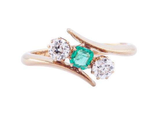 EDWARDIAN EMERALD AND DIAMOND THREE-STONE CROSSOVER RING, 1909